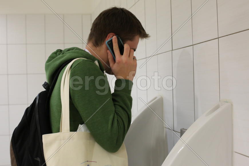 Человек разговаривает по телефону в туалете
