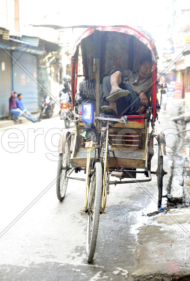 Непальский рикша спит в ожидании клеентов в своем транспорте в Катманду