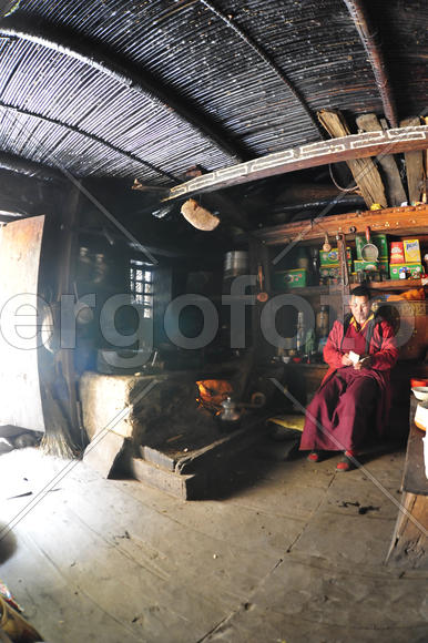 Тибетская монахиня в Непале считает деньги в своем темном доме у очага