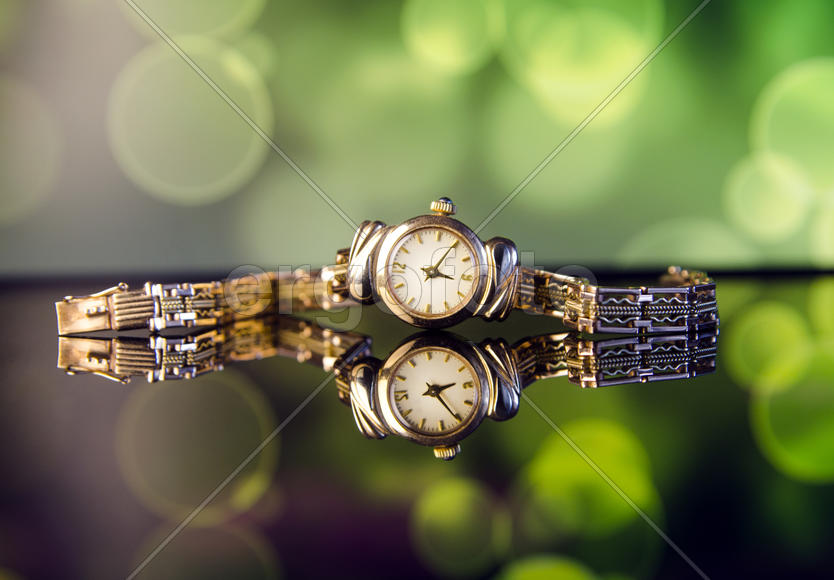 Old beautiful gold watch on a green background
