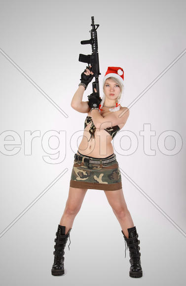 Девушка в камуфляже и шапке Санта Клауса с автоматом.