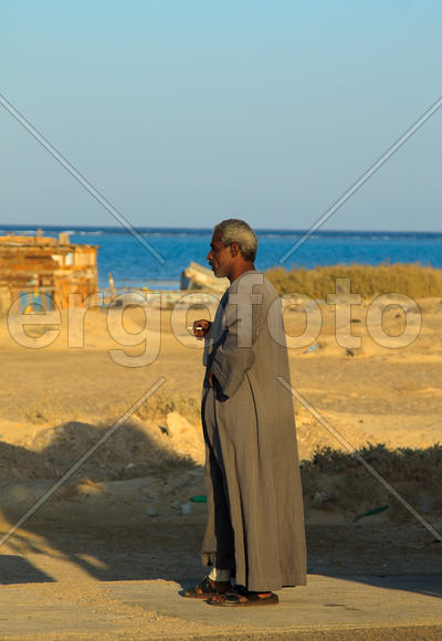 Мужчина араб с сигаретой на фоне моря и песка