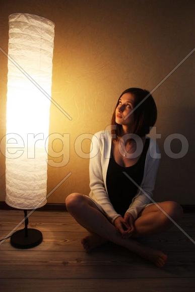 девушка, сидящая на полу у торшера