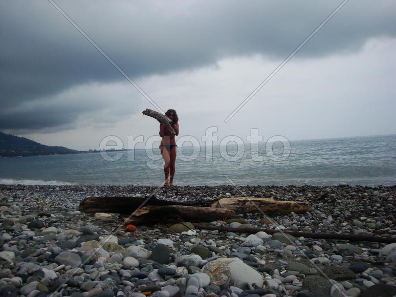 девушка на море держит полено