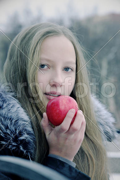 Молодая русая девушка держит в руках красное яблоко