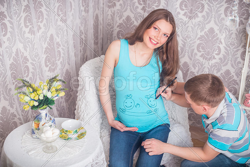 Муж рисует фламастером на футболке беременной жены