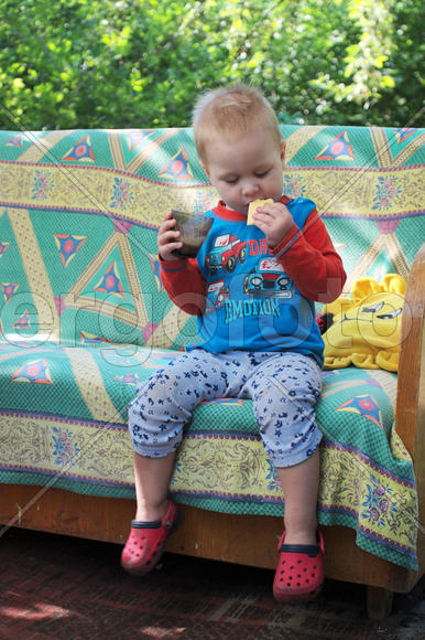 Мальчик есть печенье на диване