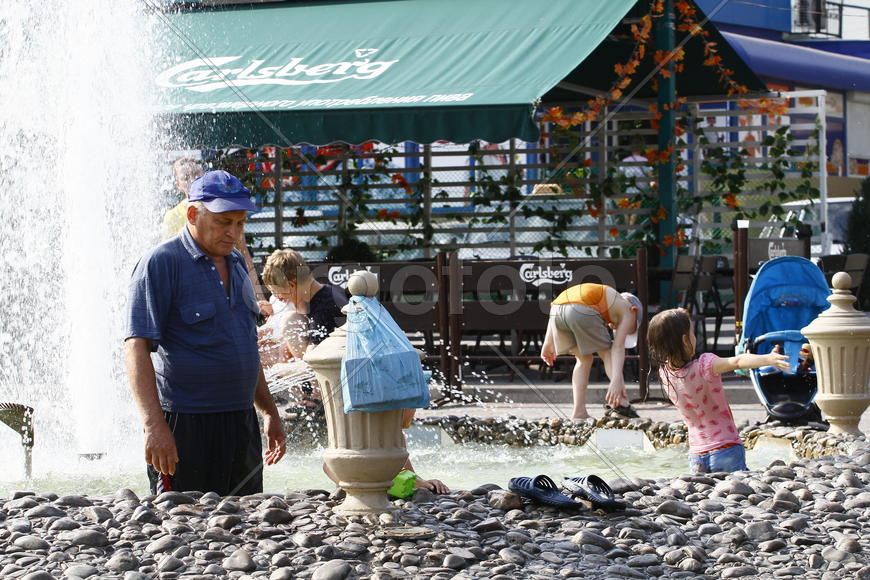 Люди купаются в фонтане летом 