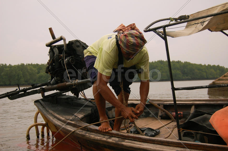 Тайский владелец лодки занят своим делом