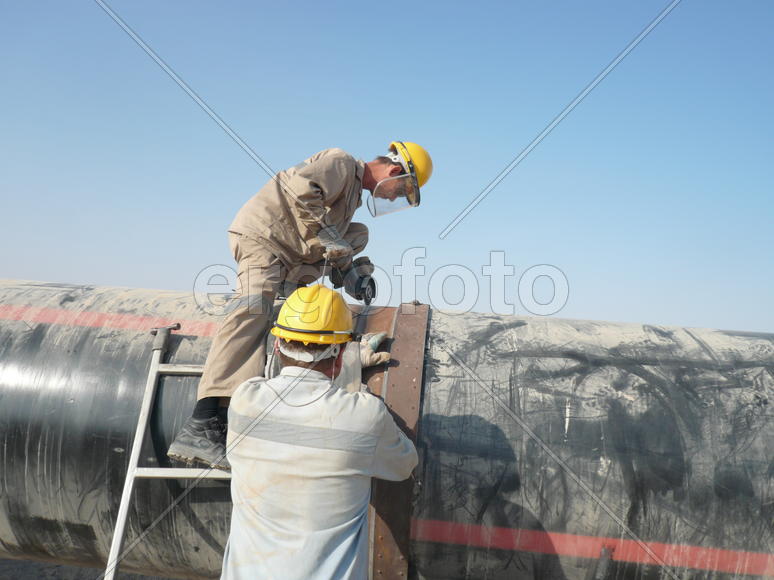 Cleaning of welding seams on the pipeline the grinder. Process of creation of welding connection