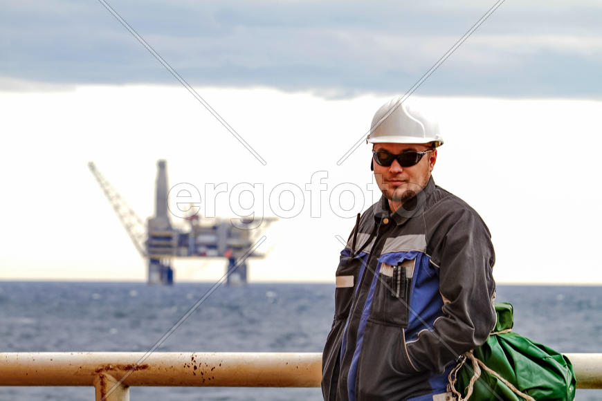 Нефтяник на палубе корабля на фоне морских платформ 