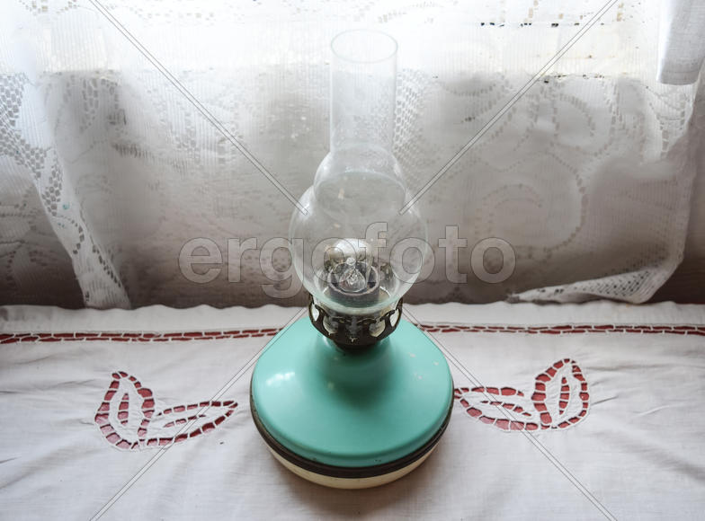 Керосиновая лампа на столе возле окна.