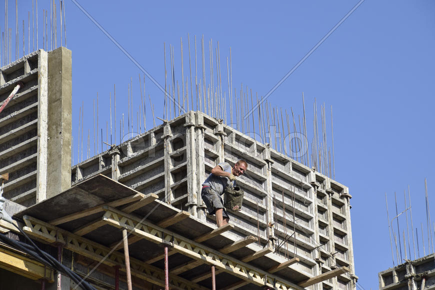 Worker pouring cement. Construction of a multistory building.
