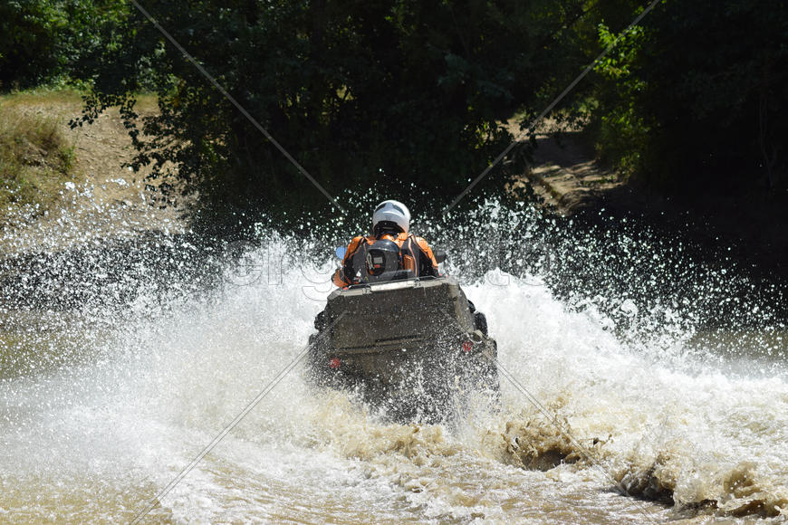 The man on the ATV crosses a stream. Tourist walks on a cross-country terrain