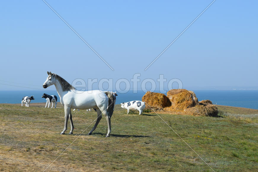 Белый конь. Фигуры лошадей сделаны из пластика на лужайке.