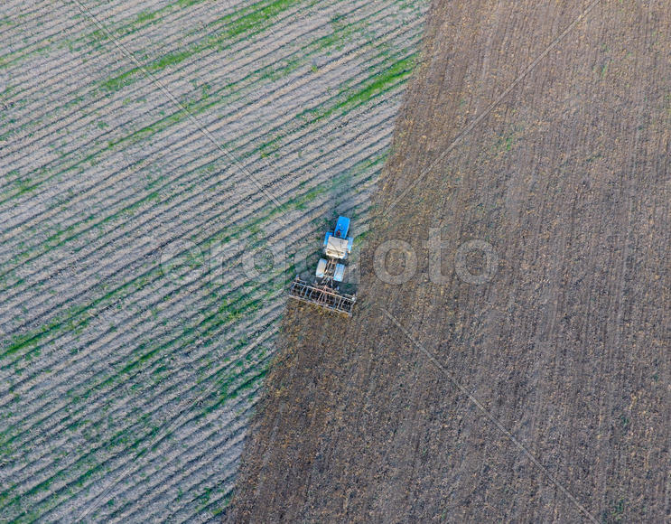 Вид сверху на трактор, который пашет поле. 