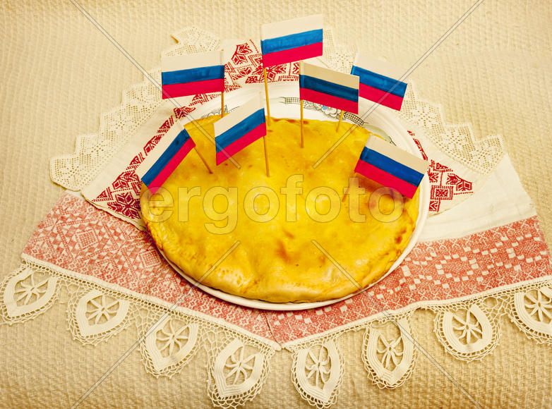 Russian pie lies on a dish with patriotic flags