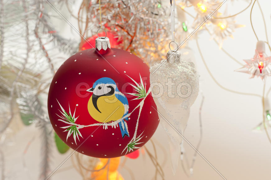 Red christmas toy with bullfinches in the form of a ball hanging on a branch
