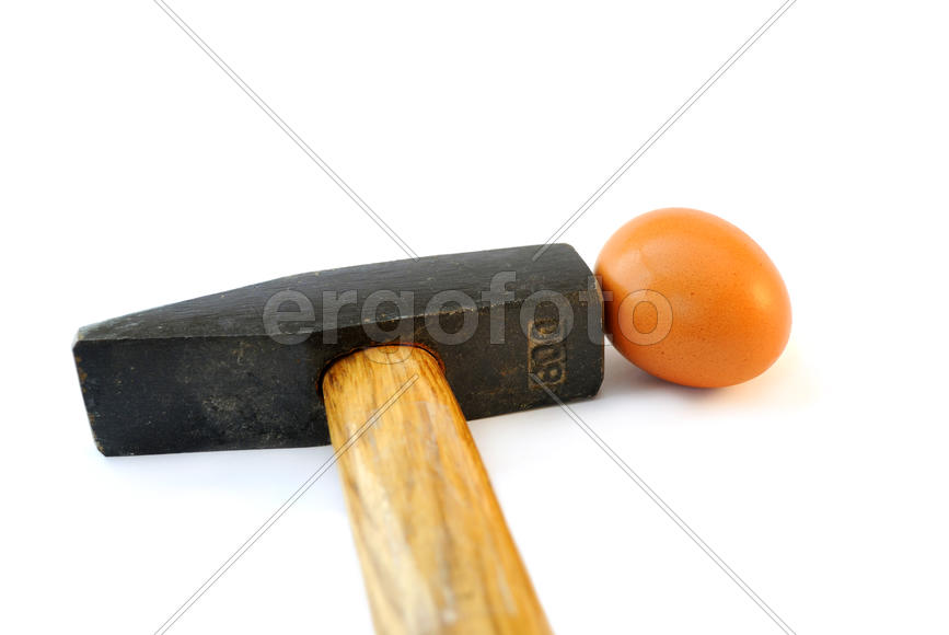  Маленькое яйцо и тяжелый молот на белом фоне.