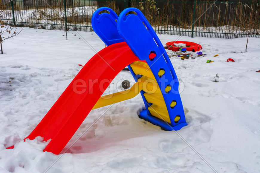 Детские аттракционы, покрытые снегом во дворе частного дома