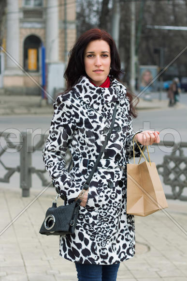Young beauty girl in casual clothes with shopping bag walking through street