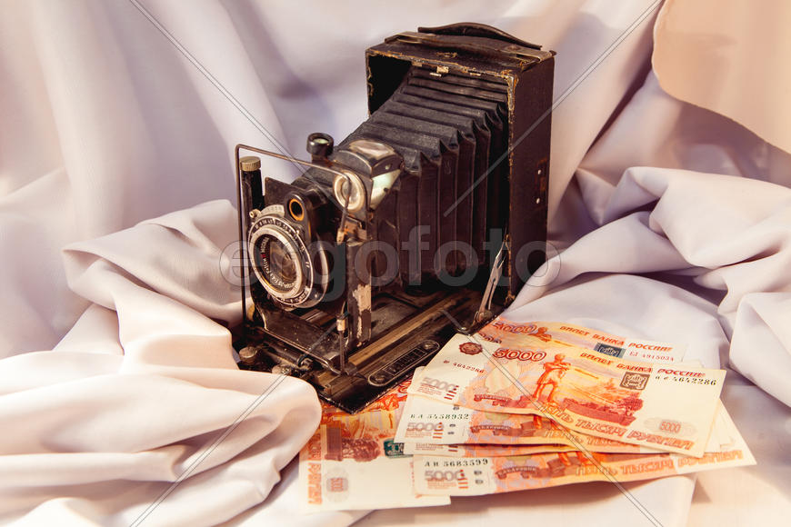 Старинный фотоаппарат и денежные купюры на ткани