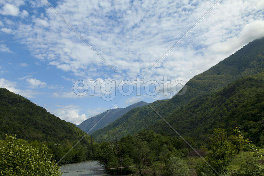 Mountains are covered with snow and the wood and surrounded with clouds