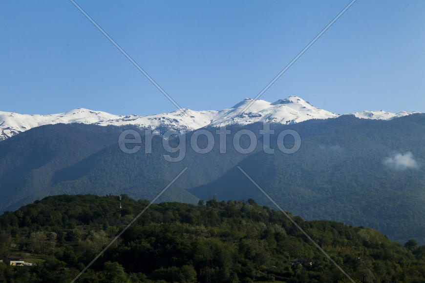 Mountains are covered with snow and the wood and surrounded with clouds