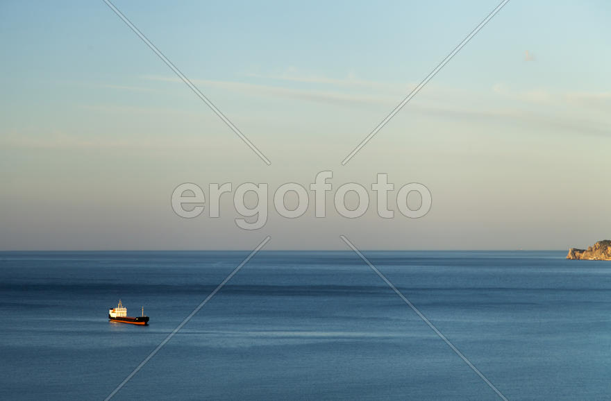 Mountains by the sea at sunrise in beams of the soft sun