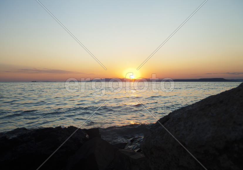 The sea at sunset in beams of the red setting sun