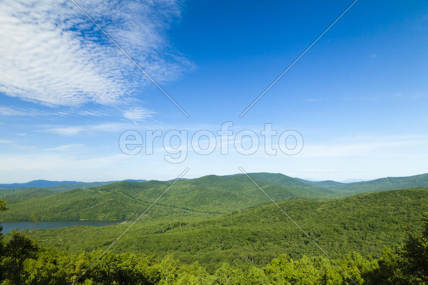 Green hills under the blue sky in beams of a bright sun