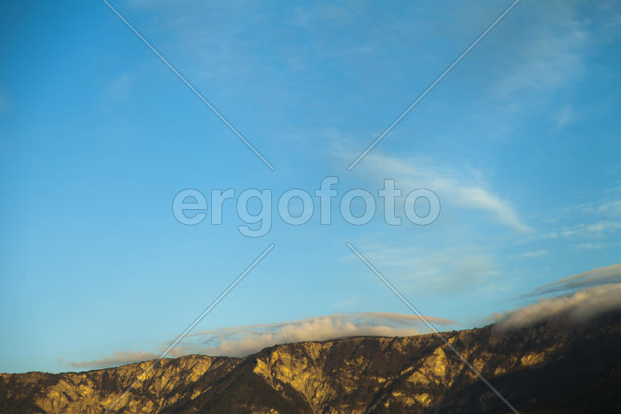 Mountains by the sea at sunrise in beams of the soft sun