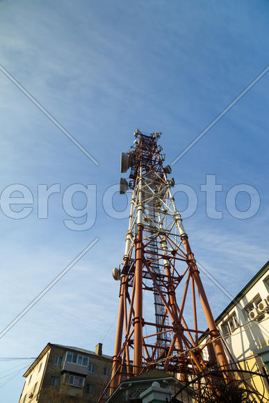 Communication tower against the bright blue sky with clouds