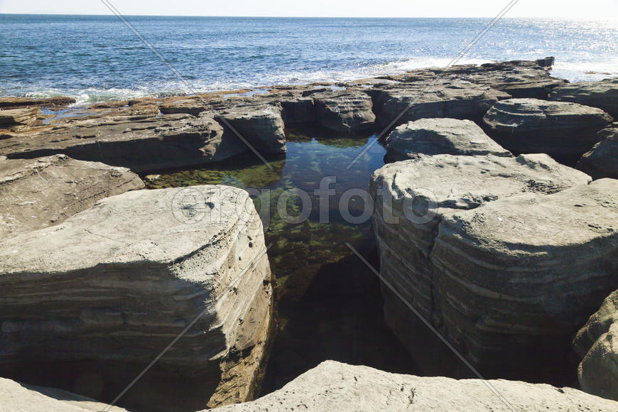 Rocks and sea meet in the bright sunlight in autumn