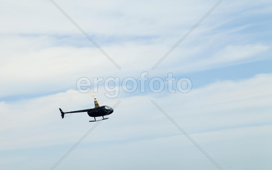 The helicopter in the sky turns over the sea, entertaining people