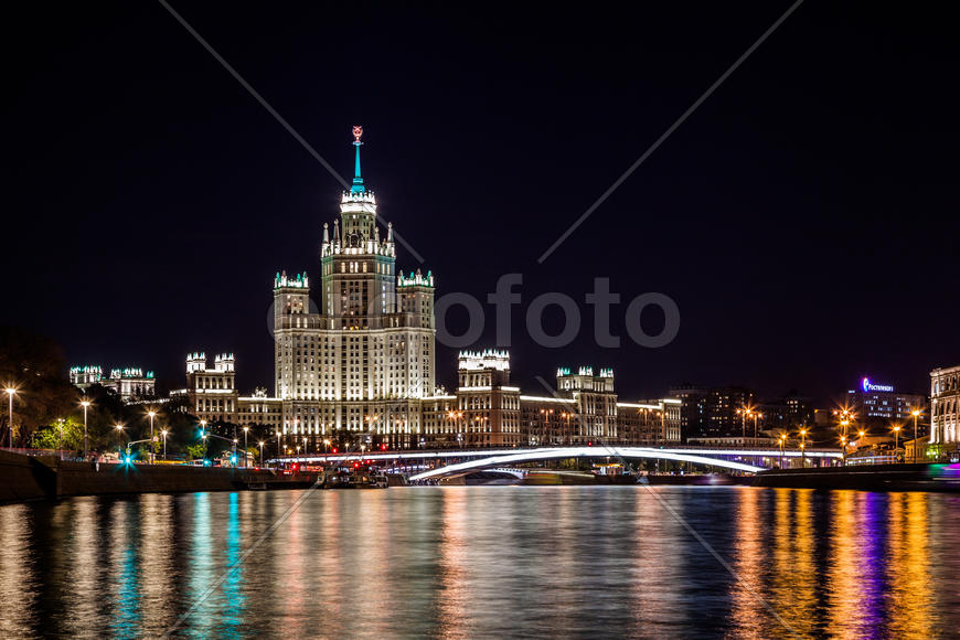 Вид на фасад одной из сталинских высоток Москвы через реку вечером, Россия