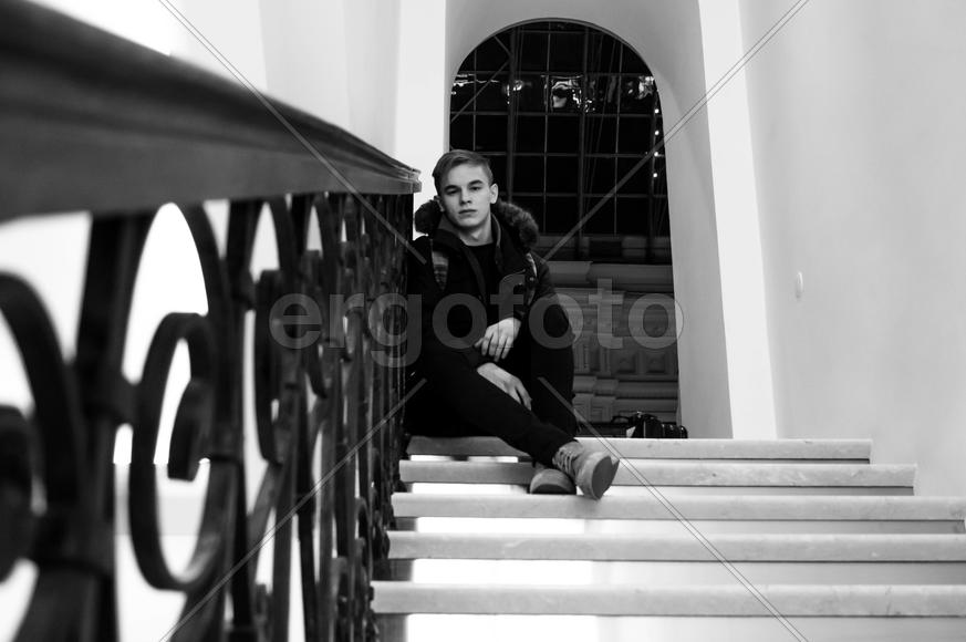 Молодой парень сидящий на ступеньках