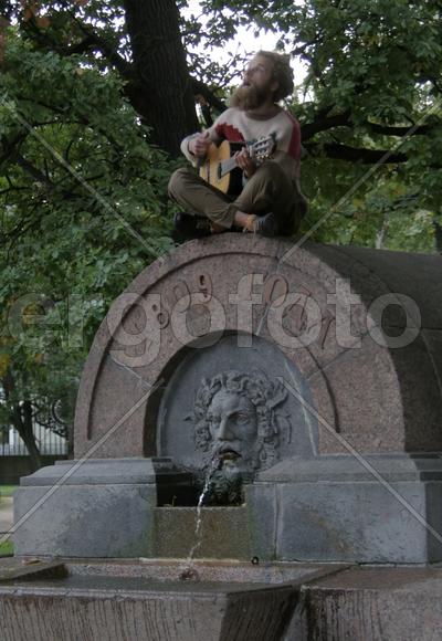 Уличный музыкант сидид на фонтане. Санкт-Петербург 2016 