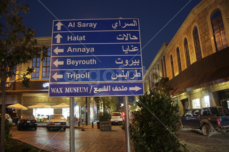 Ливан. Указательный знак с видом на ночную улицу, освещенную фонарями.
