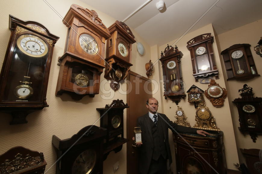 Коллекционер в окружении старинных механических часов 