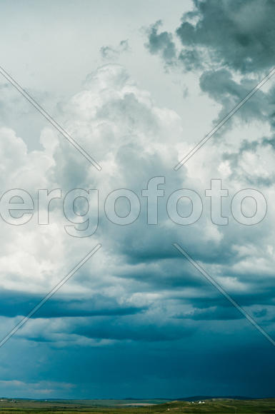 Ярко голубые облака на небе над зеленым лугом 