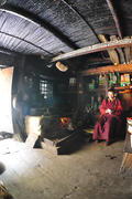 Тибетская монахиня в Непале считает деньги в своем темном доме у очага