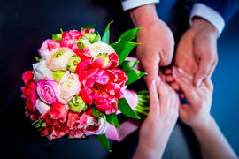 Красочный букет невесты на фоне рук молодоженов