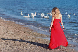 Девушка-блондинка в красном на фоне моря