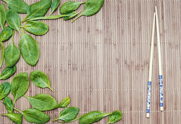 spinach leaves on a bamboo mat and bamboo chopsticks