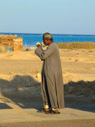 Мужчина араб прикуривает сигарету на фоне моря и песка