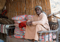 Пожилой мужчина-араб, бедуин, сидит на топчане в шалаше