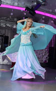 Девушка-блондинка танцует в бирюзовом платье