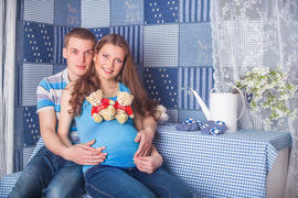 Муж и беременная жена сидят за клетчатым столом
