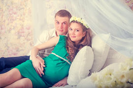 Муж и беременная жена на диване с подушками